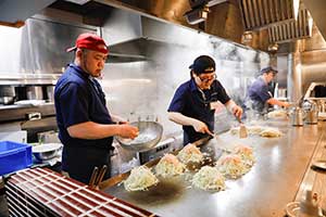 広島流お好み焼みっちゃん厨房でお好み焼きを調理するスタッフ